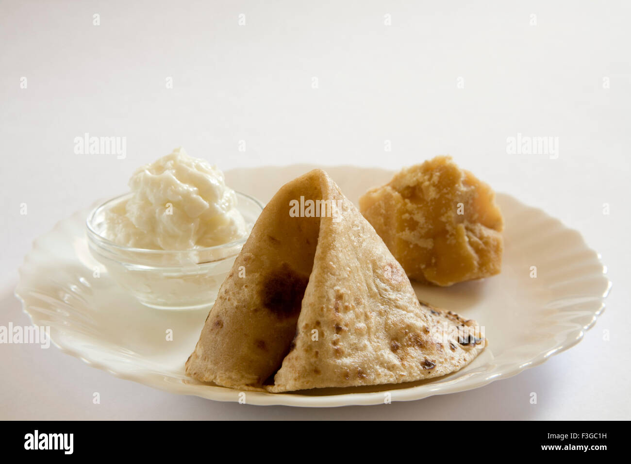 Indisches Essen nach Hause gemachte Butter mit Jaggery Gur und Paratha indisches Brot in Teller gedient; Indien Stockfoto