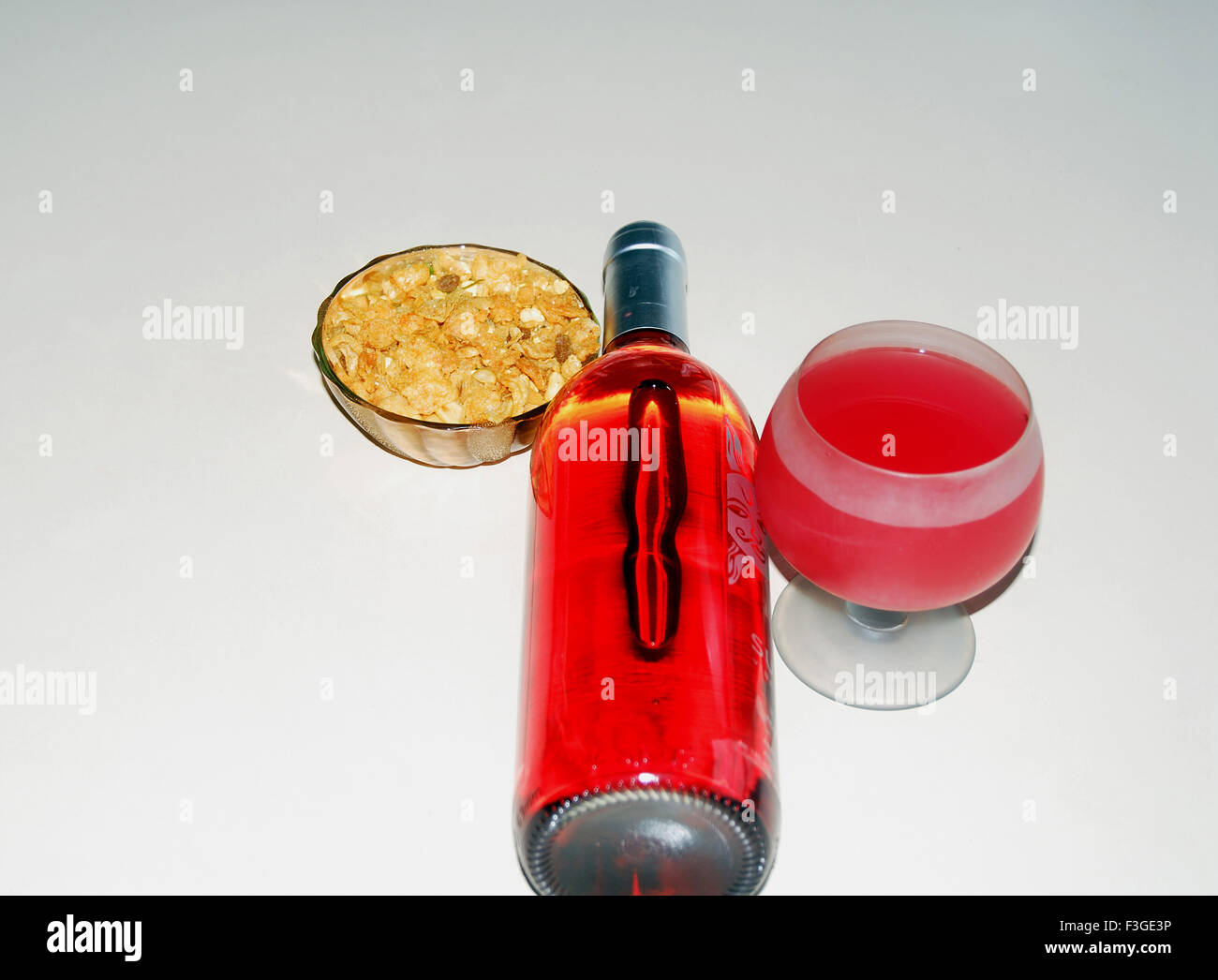 Getränke; Ein Glas Rotwein und Flasche Snacks Schüssel neben Männer Paradies Glück Freude Stockfoto