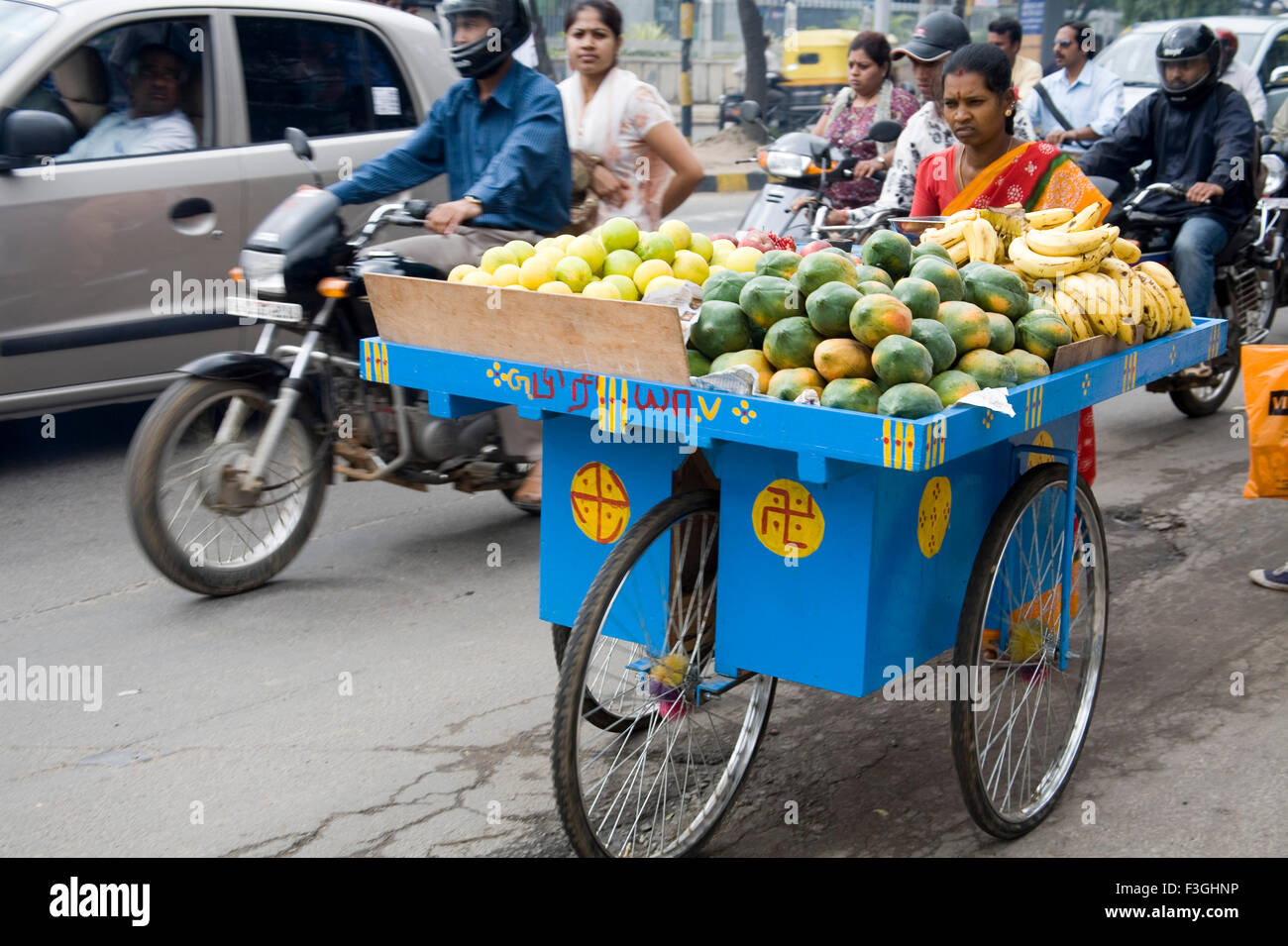 Indische Frau verkaufen Früchte auf blau drei Wheeler Warenkorb Verkehr auf Straße; M G Road Bangalore; Karnataka; Indien Stockfoto