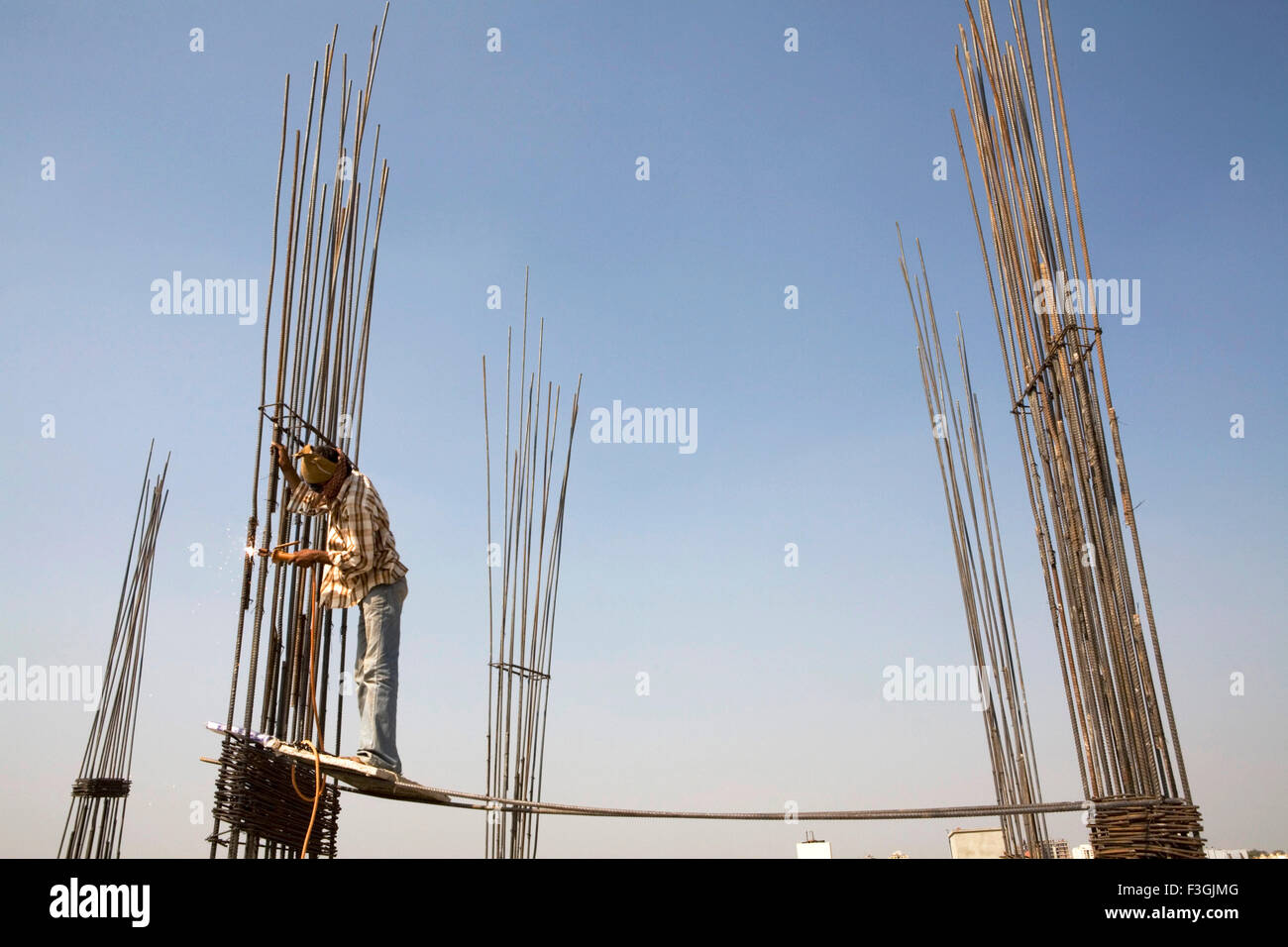 Ein Schweißer prekär ohne Helm und Sicherheitsgurt auf einer Baustelle stehen; Ahmedabad; Gujarat; Indien Stockfoto