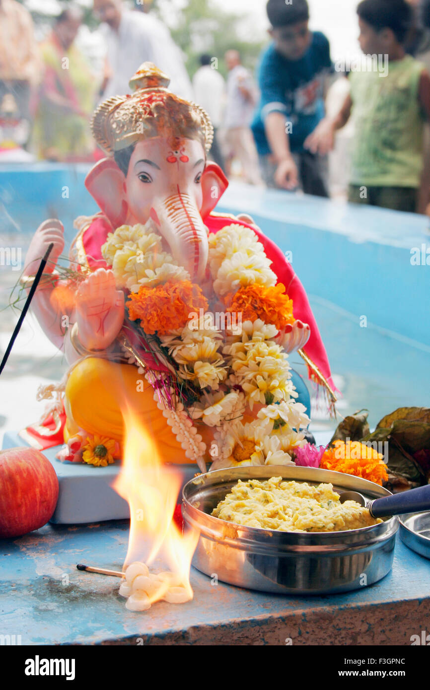Kleines Idol von Lord Ganesh Elefant ging Gott bereit, mit kleinem Feuer und süßen davor bietet eingetaucht; Pune Stockfoto