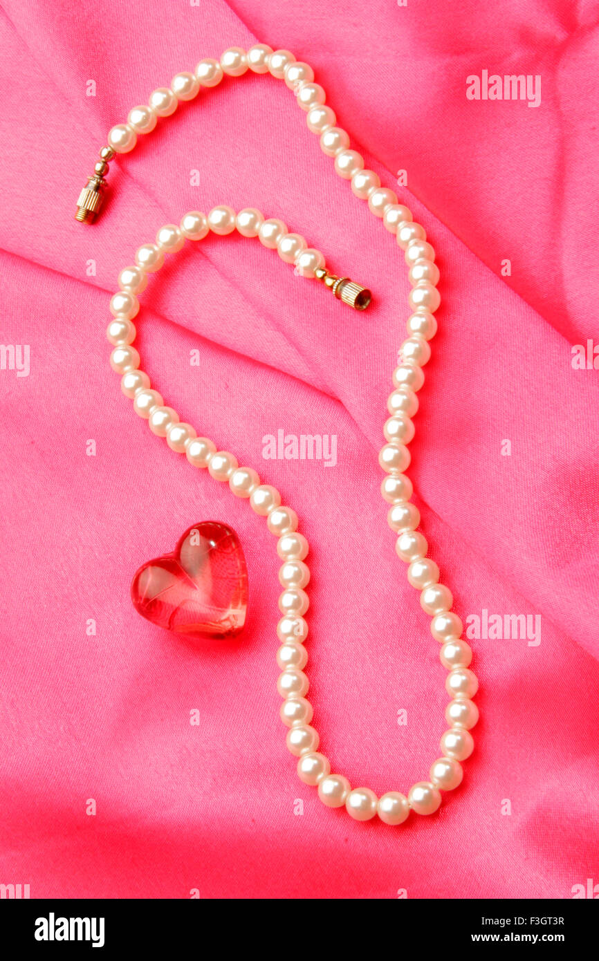 Schmuck in Form Perle Halskette mit synthetischen roten Edelstein der Herzform rosa satin Hintergrund Stockfoto