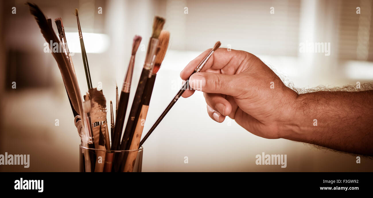 Des Malers Hand unter einer Bürste in einem Topf Stockfoto