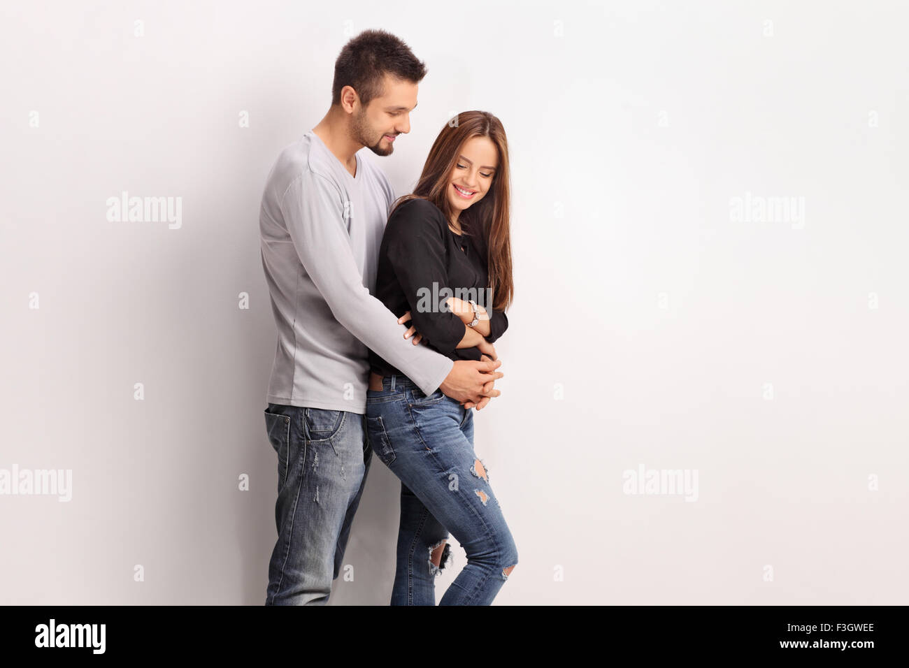 Junge romantische Paar umarmt und posieren gegen eine graue Wand Stockfoto