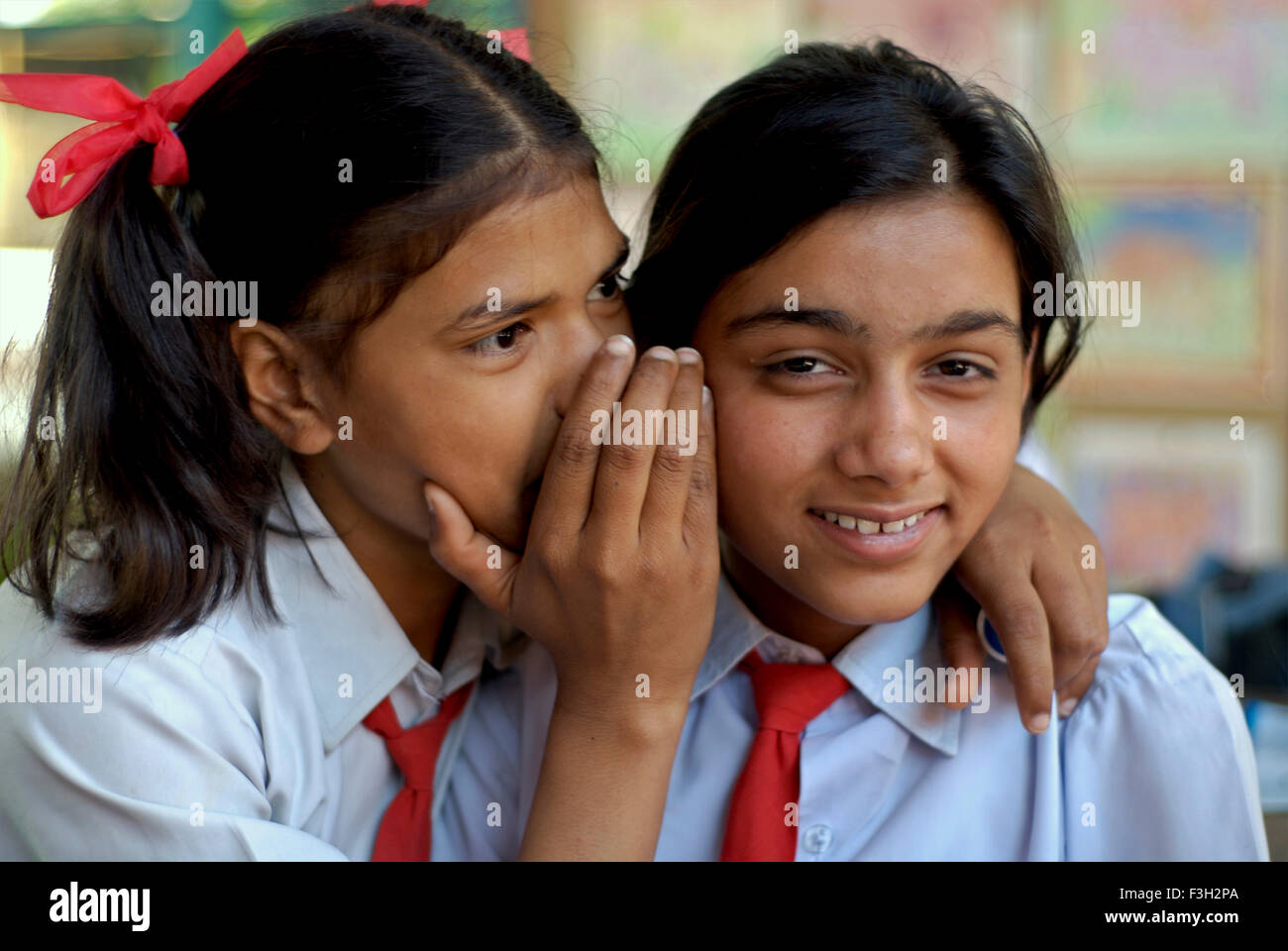 Ein Mädchen in ein anderes Mädchen Ohr am Nanhi Dunya Flüstern; Dehradun; Uttaranchal; Indien Herr #711 Stockfoto