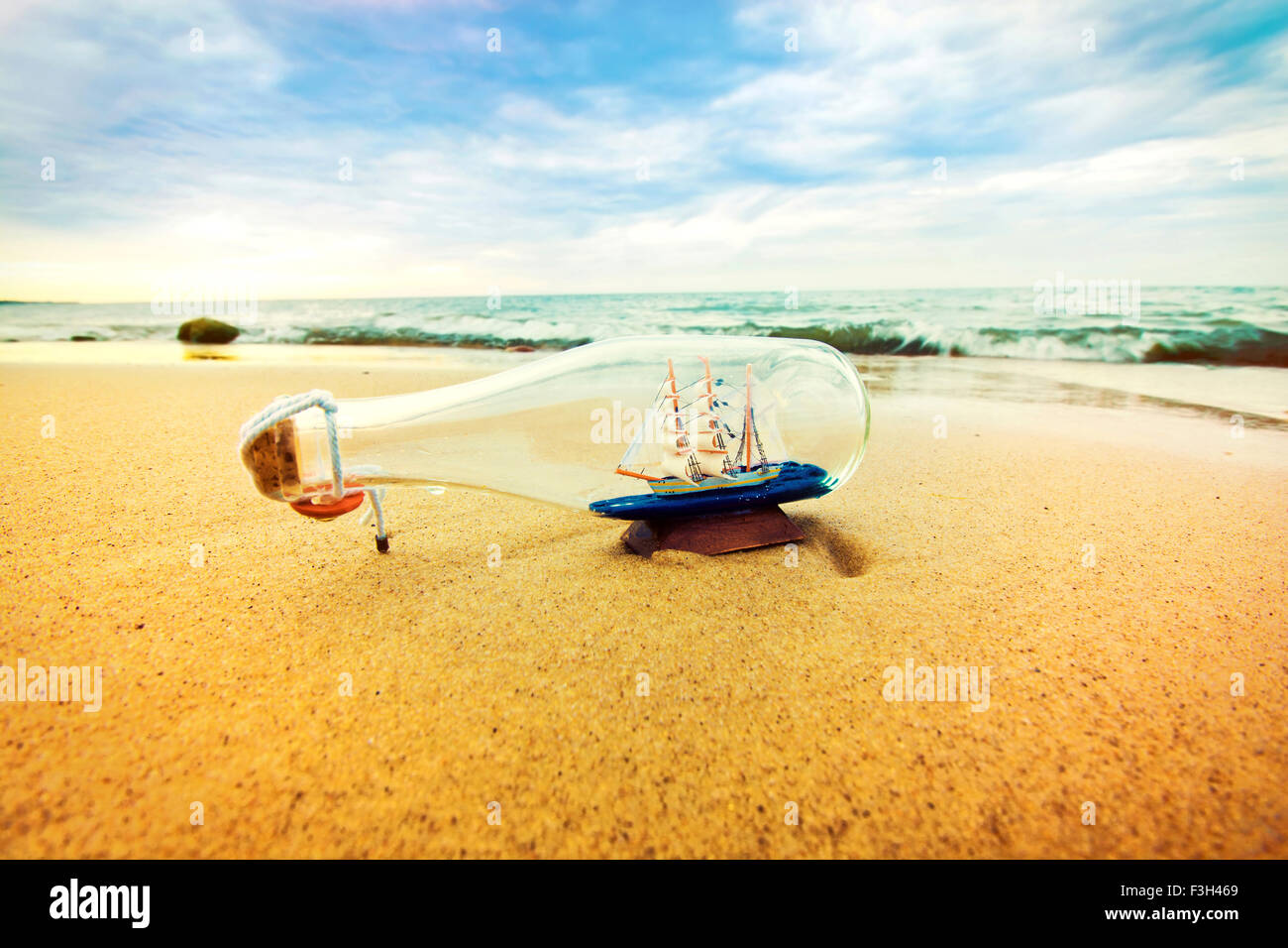 Flasche mit Schiff innen am Strand liegen. Souvenir-Konzeptbild. Natur im Paradies. Stockfoto