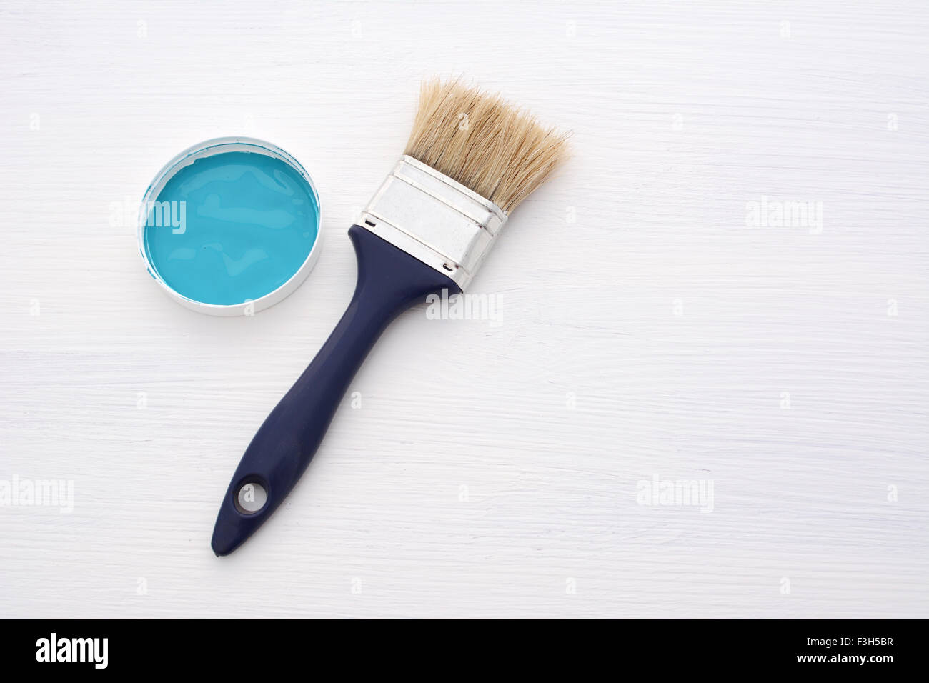 Saubere Pinsel und kleinen Behälter mit blauer Farbe auf einem Holzbrett, weiß lackiert Stockfoto