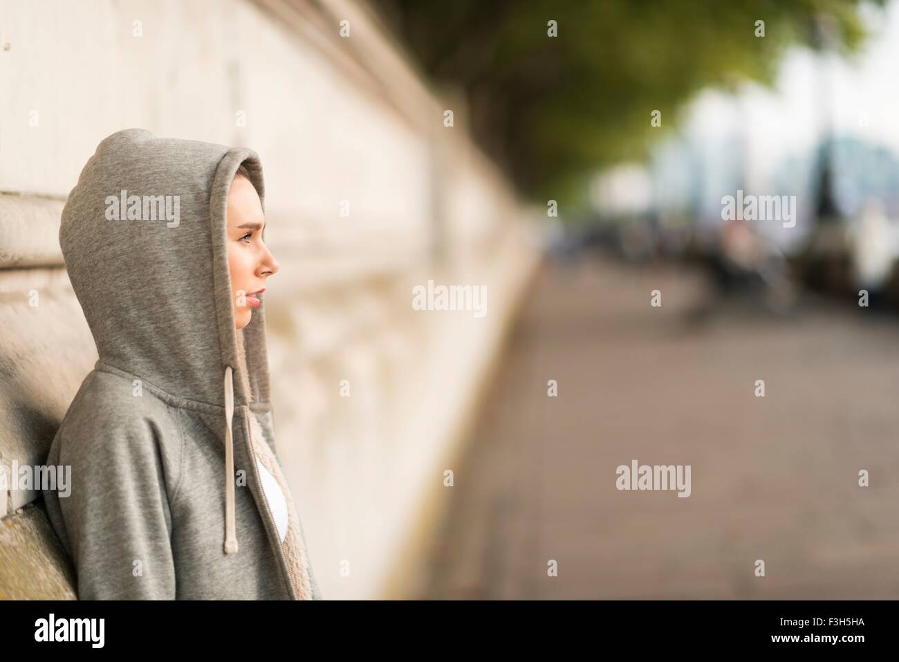 Junge Frau trägt graue Kapuzenjacke mit Blick vom riverside Stockfoto