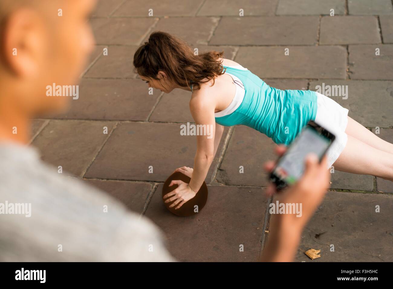 Schulter-Blick über Trainer Timing Läuferinnen Push-Ups auf smartphone Stockfoto