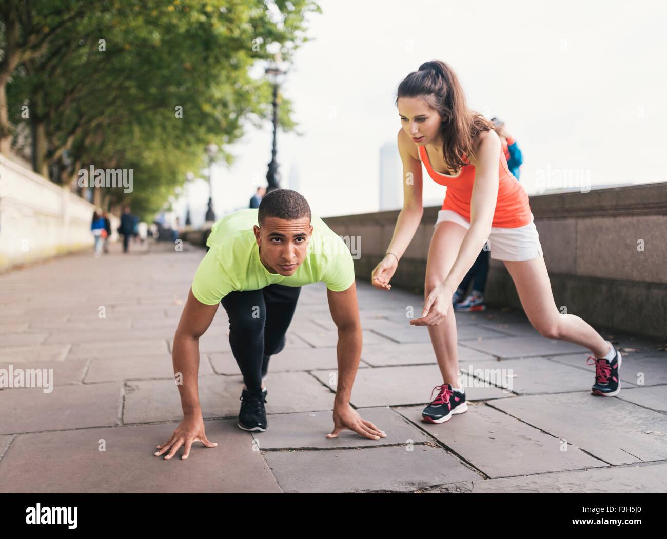 Junge weibliche Trainer fördern männliche Läufer am Ufer Stockfoto