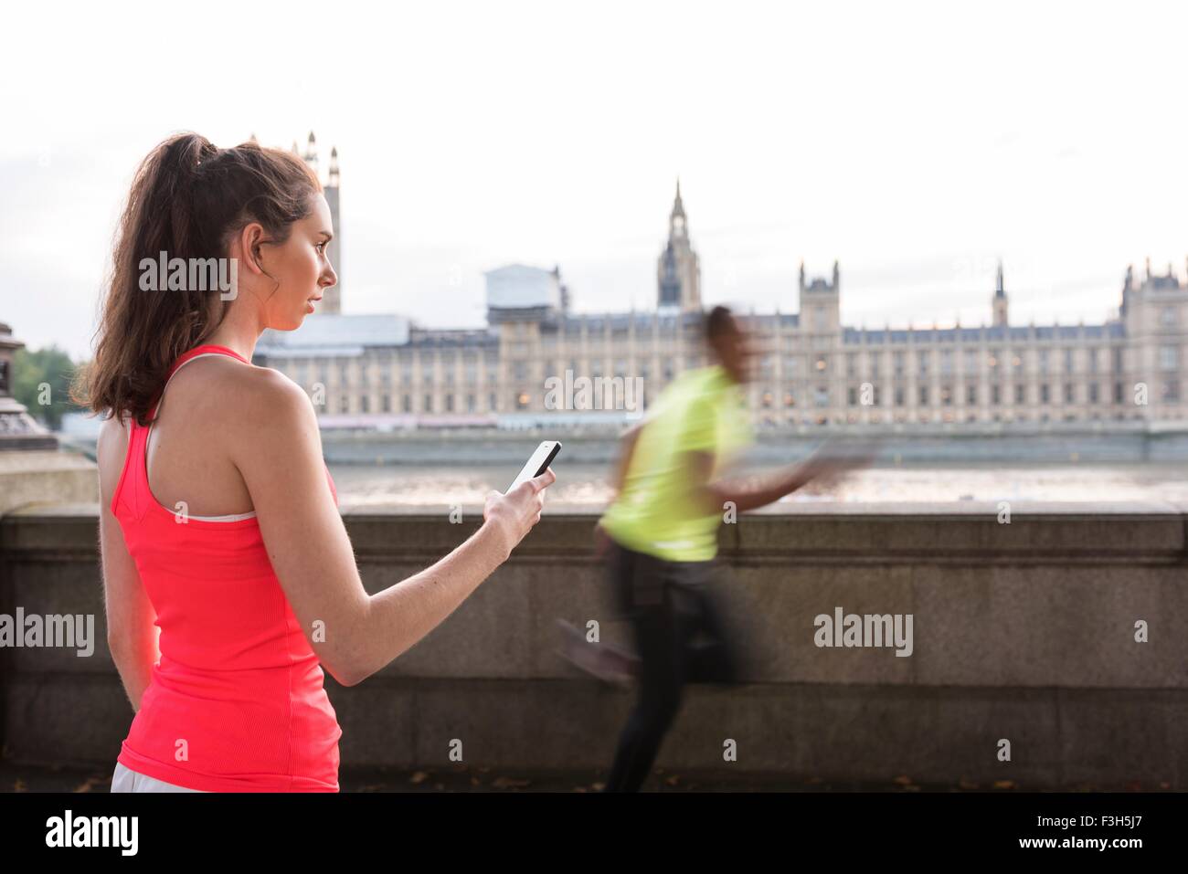 Weibliche Trainer Timing männliche Läufer am Southbank, London, UK Stockfoto