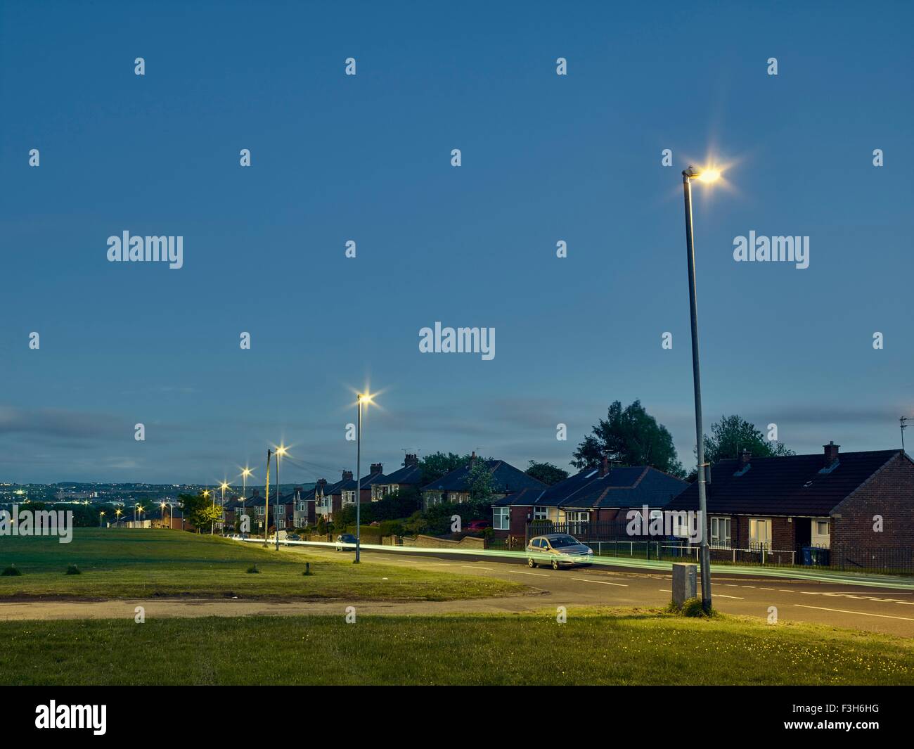 Lichtspuren auf Straße in der Nacht in Wohngebiet Stockfoto