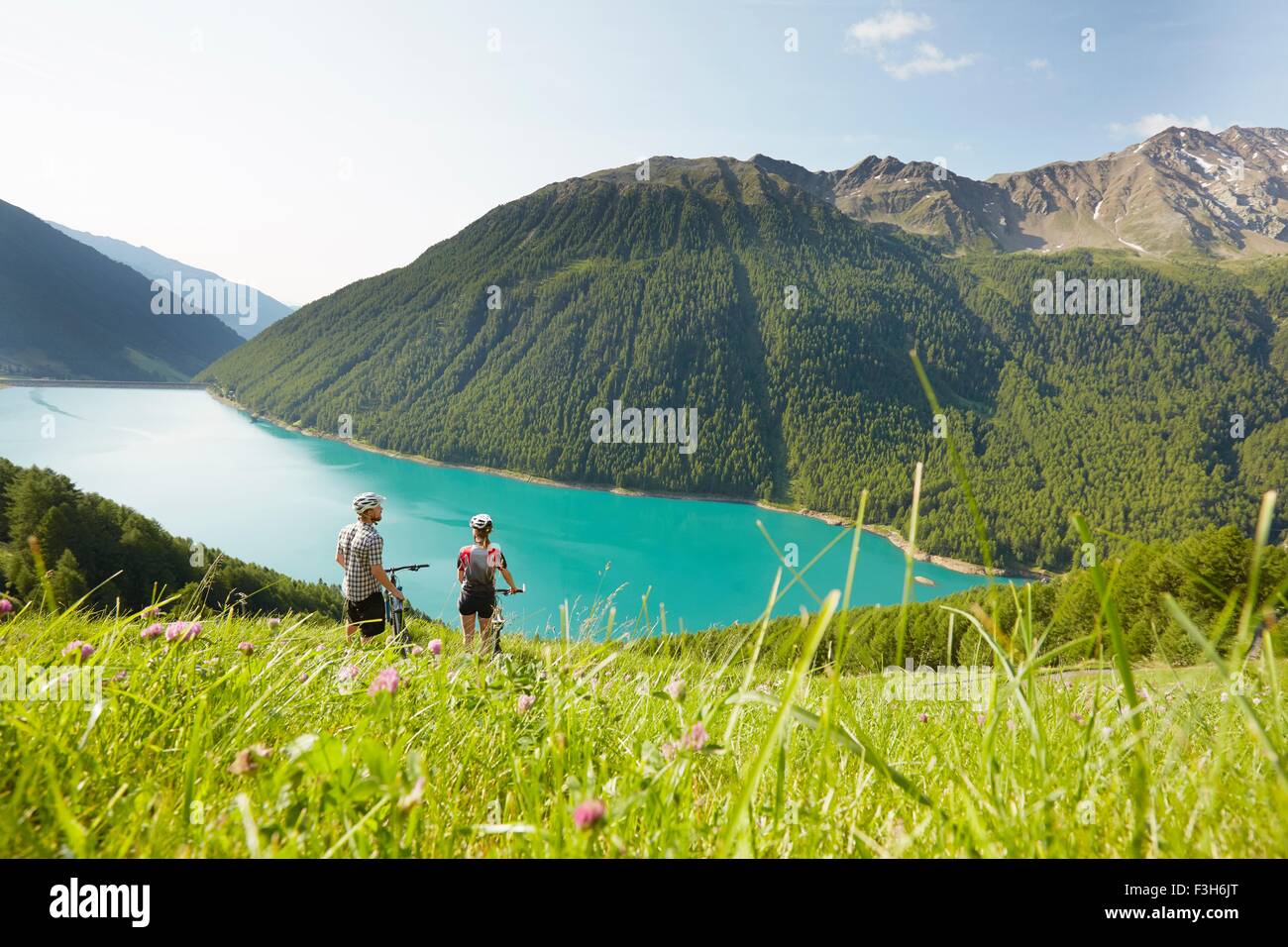 Junges Paar auf Mountainbikes mit Blick auf Vernagt Stausee, Val Senales, Südtirol, Italien Stockfoto