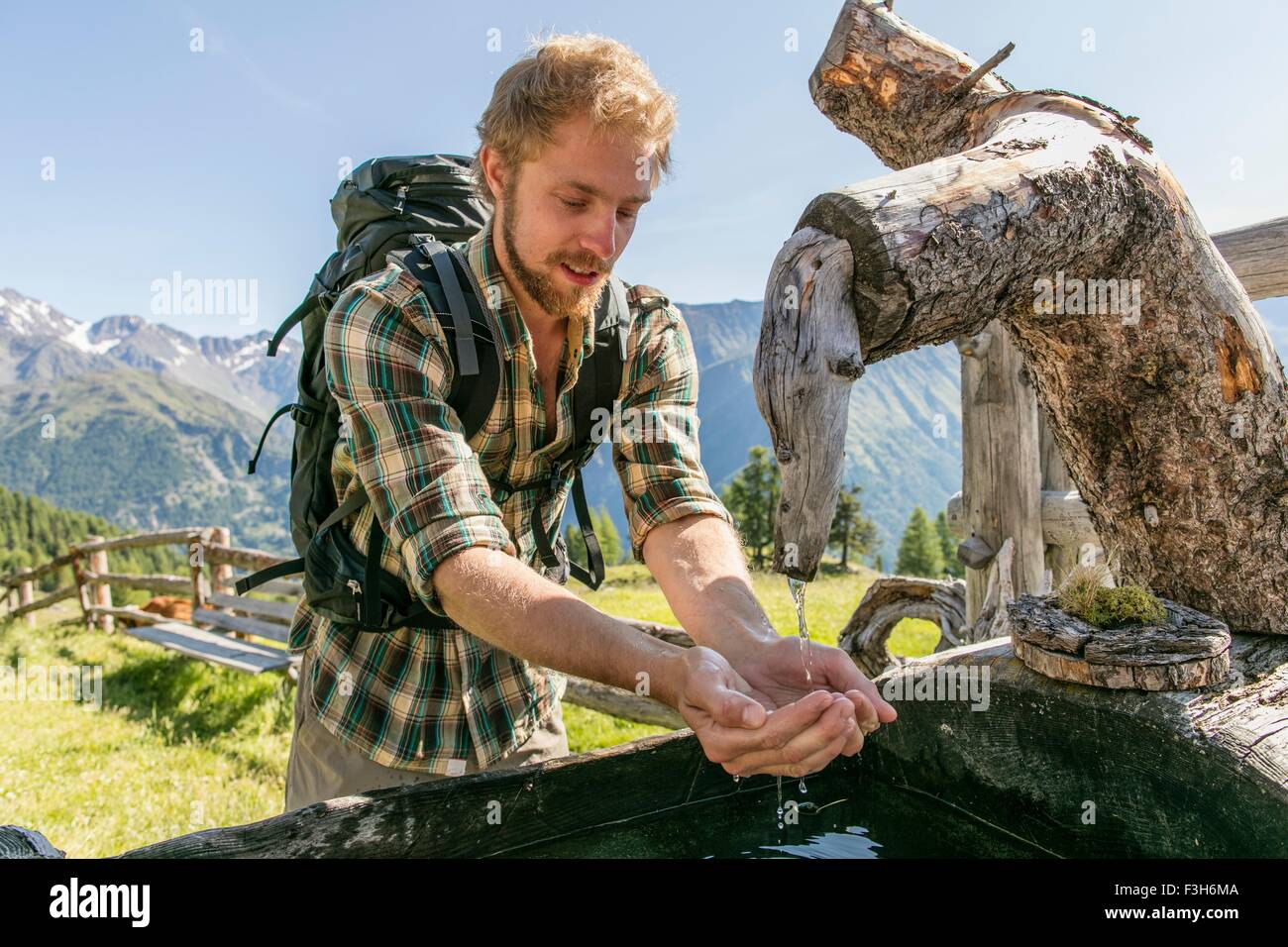 Junge männliche Wanderer Trinkwasser aus rustikalen Trog, Karthaus, Val Senales, Südtirol, Italien Stockfoto