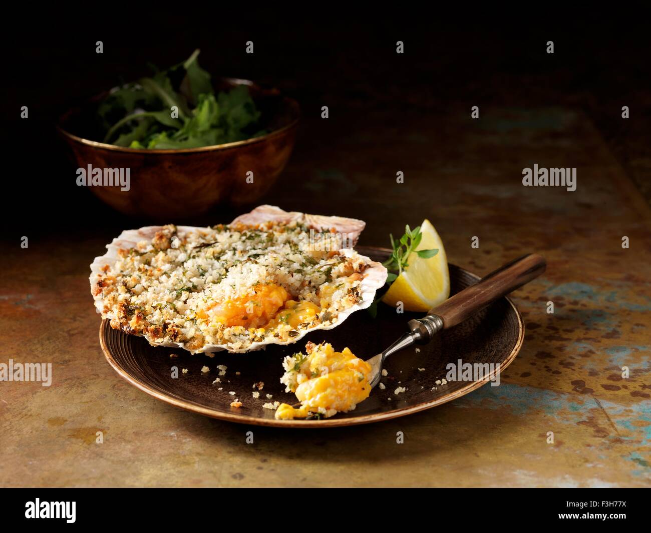 Stillleben mit Langusten und Garnelen Backen im Seashell mit Schüssel mit gemischtem Salat Stockfoto