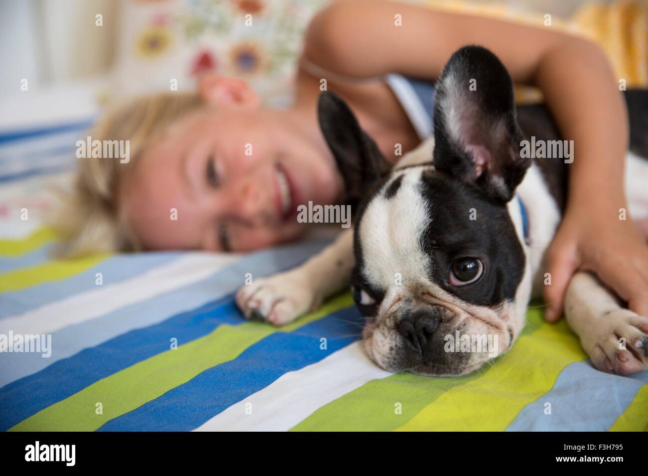 Porträt von niedlichen Hund und Mädchen auf dem Bett liegend Stockfoto