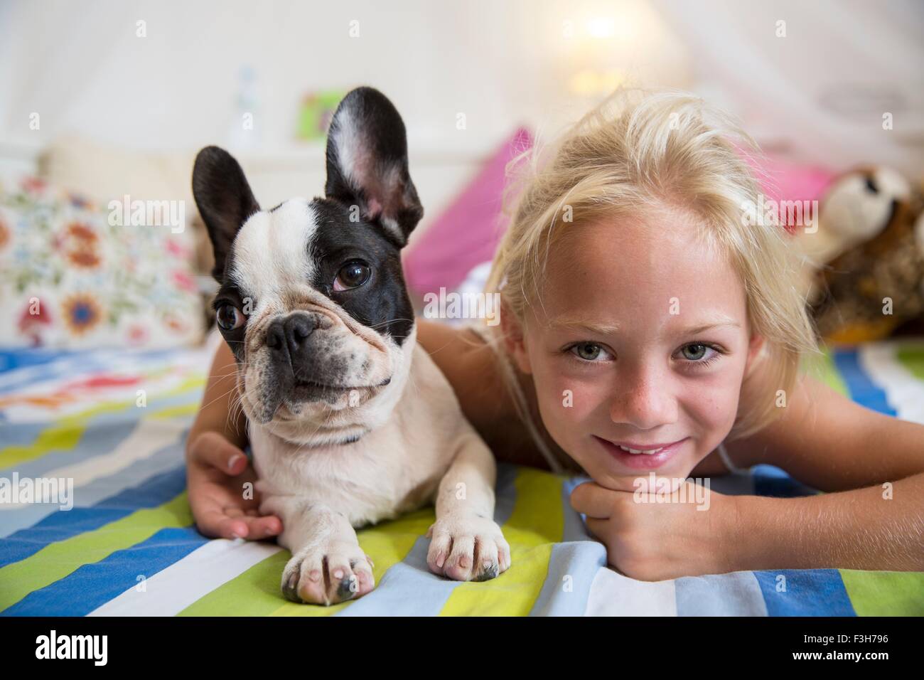 Porträt von Mädchen und niedlichen Hund auf Bett liegend Stockfoto