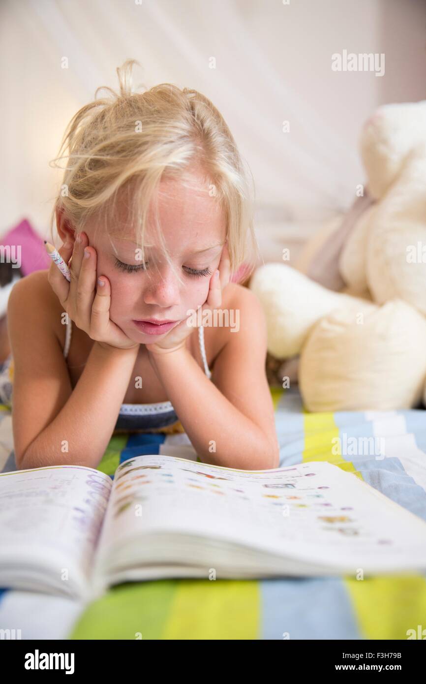 Mädchen auf Bett Blick auf Puzzle-Buch Stockfoto