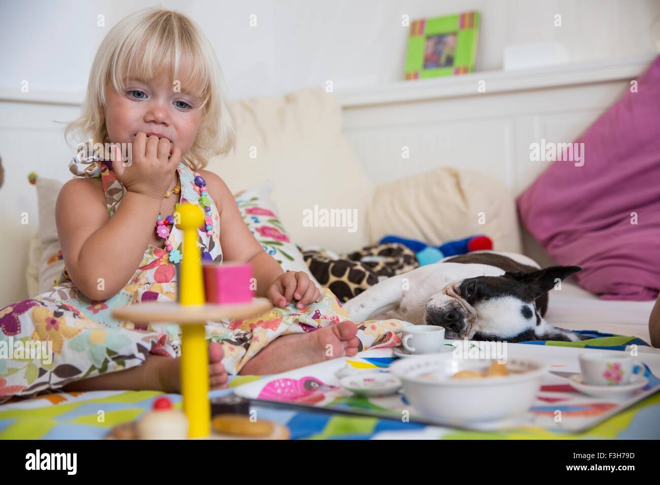 Weiblichen Kleinkind spielen mit Spielzeug-Tee-Set auf Bett Stockfoto