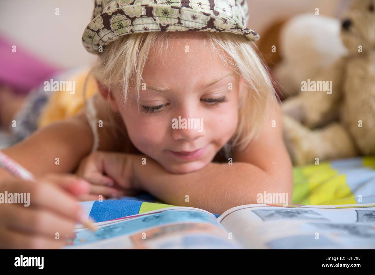 Mädchen auf Bett Blick auf Fragen in Puzzle-Buch Stockfoto
