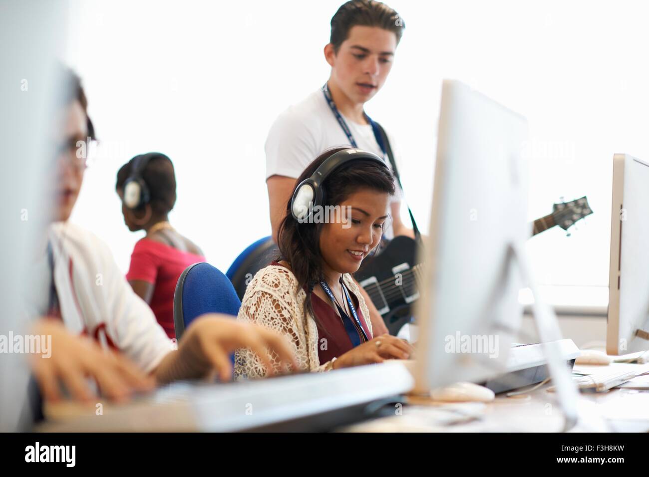 Weibliche College-Student mit Kopfhörern spielen Tastaturen blickte lächelnd Stockfoto