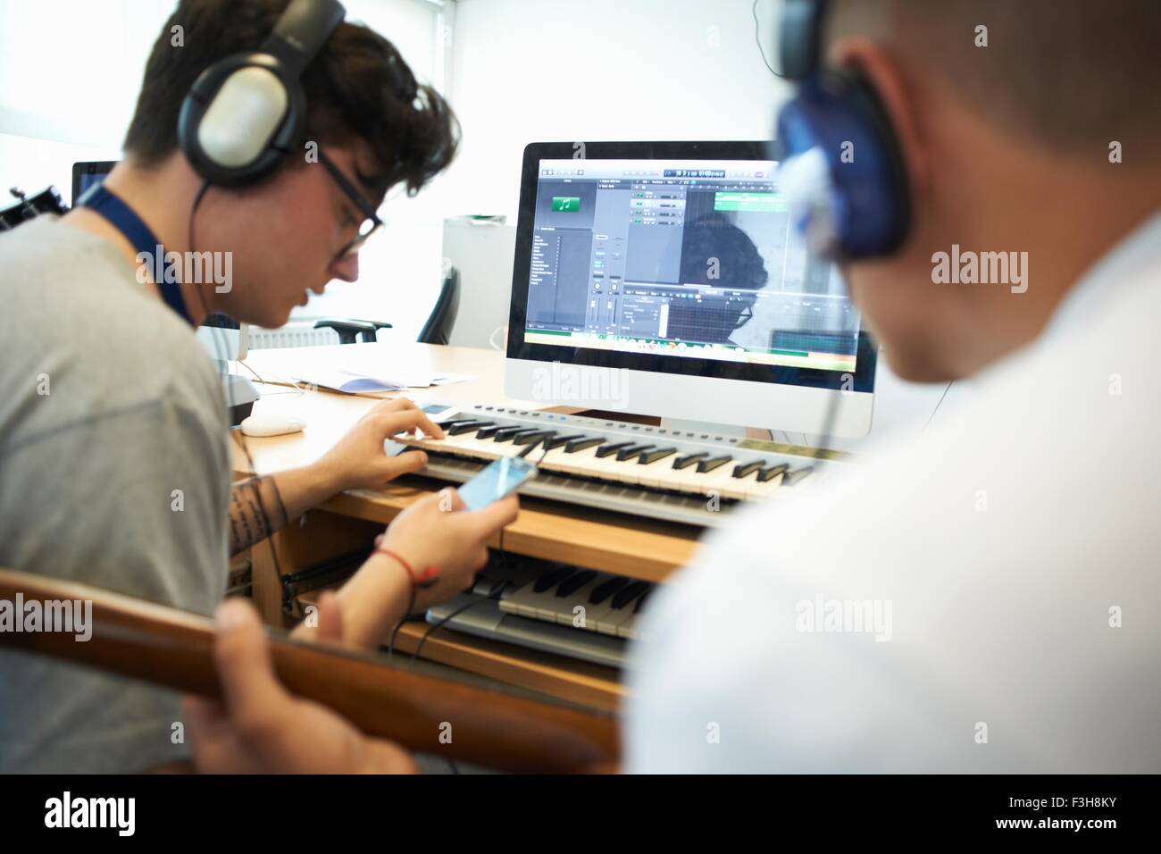 Über Schulter Blick der jungen Männer tragen von Kopfhörern mit Recording-Equipment, blickte auf smartphone Stockfoto
