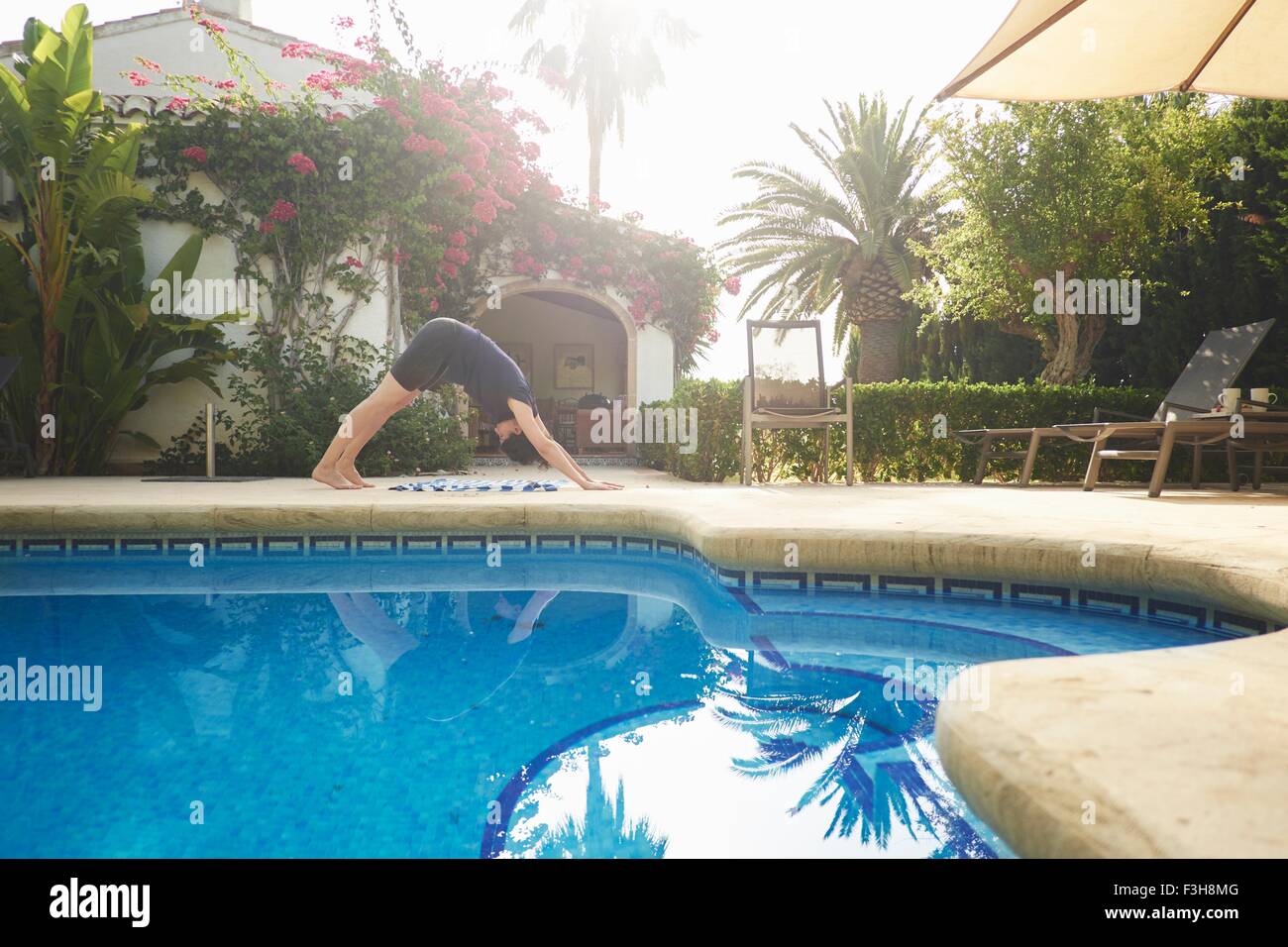 Reife Frau beim Yoga im Urlaub Apartment am Pool Stockfoto