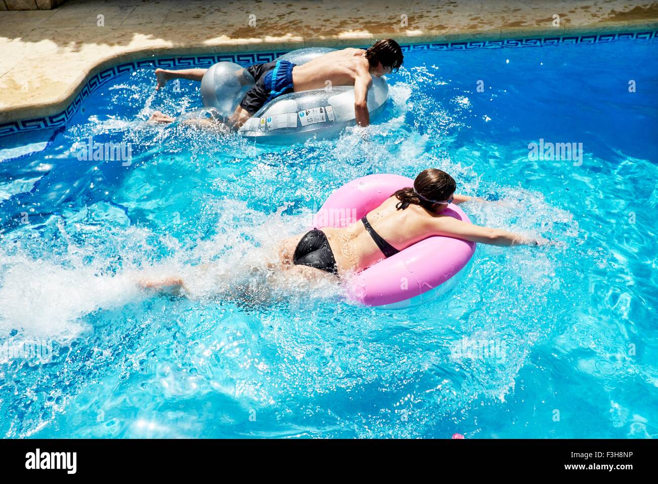 Junger Mann und Teenager Schwester racing auf Hüpfburgen im Schwimmbad Stockfoto