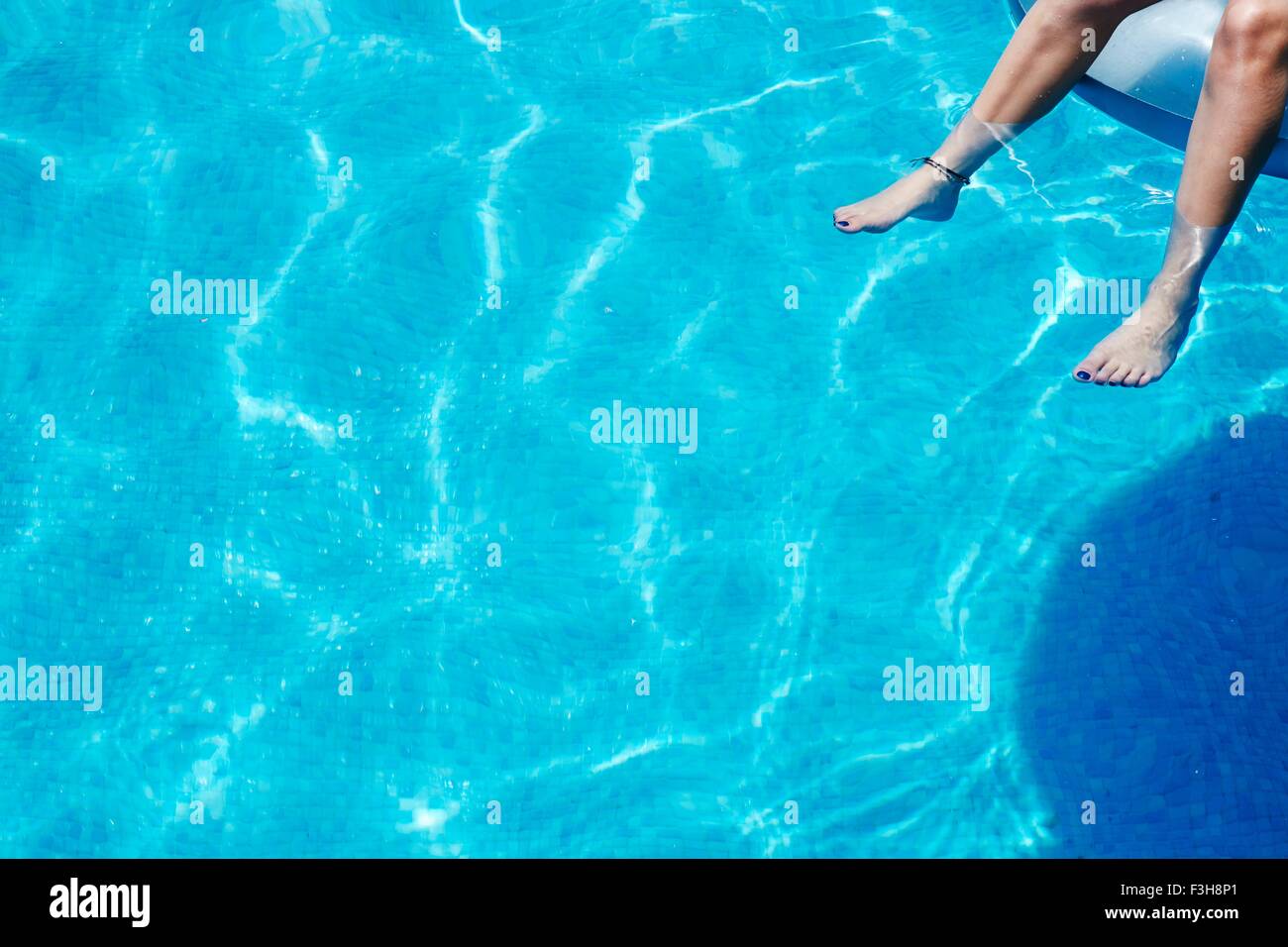 Beine und Füße des Mädchens baumelt im Schwimmbad Stockfoto