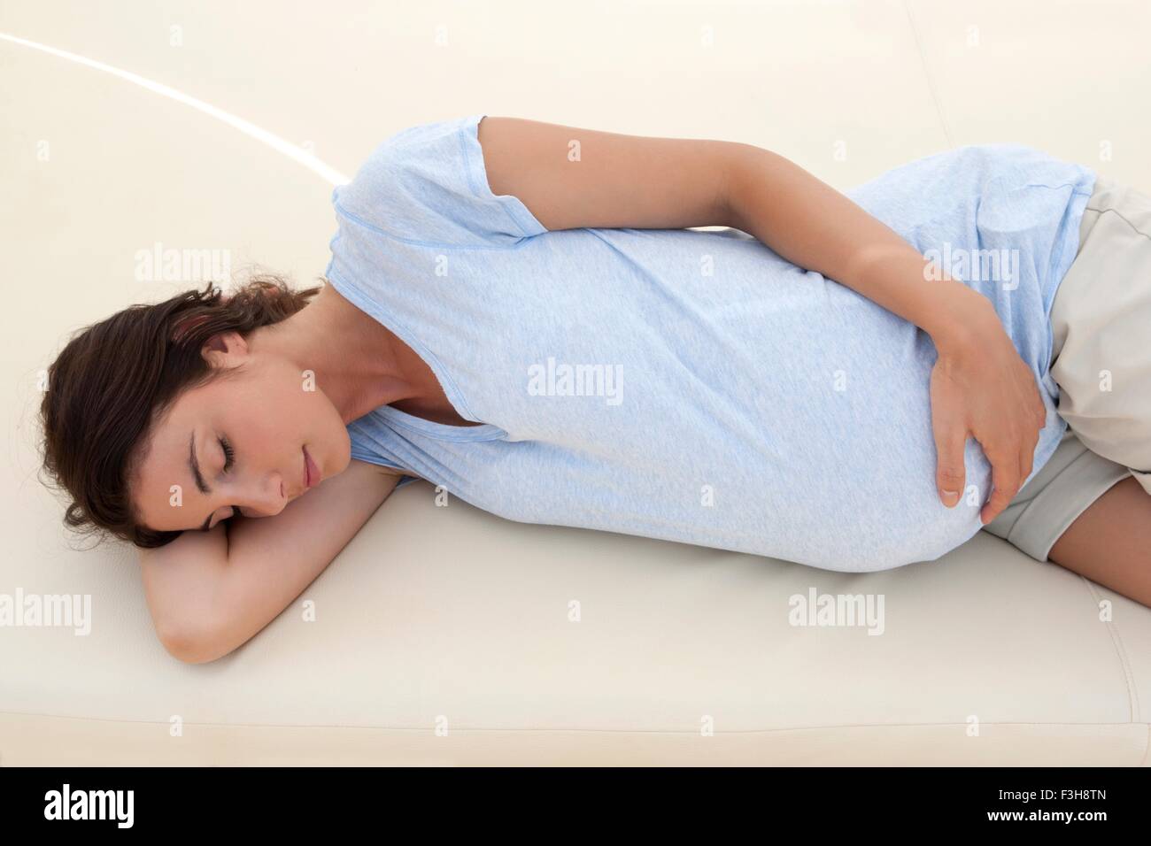 Mitte erwachsenen Frau schläft auf Liege mit Hand auf Bauch schwanger Stockfoto