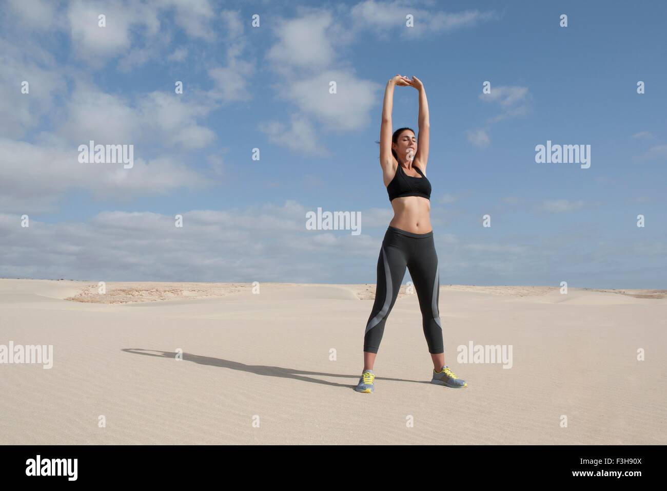 Mitte Erwachsene Frau mit am Strand erhobenen Armen Ausübung Stockfoto