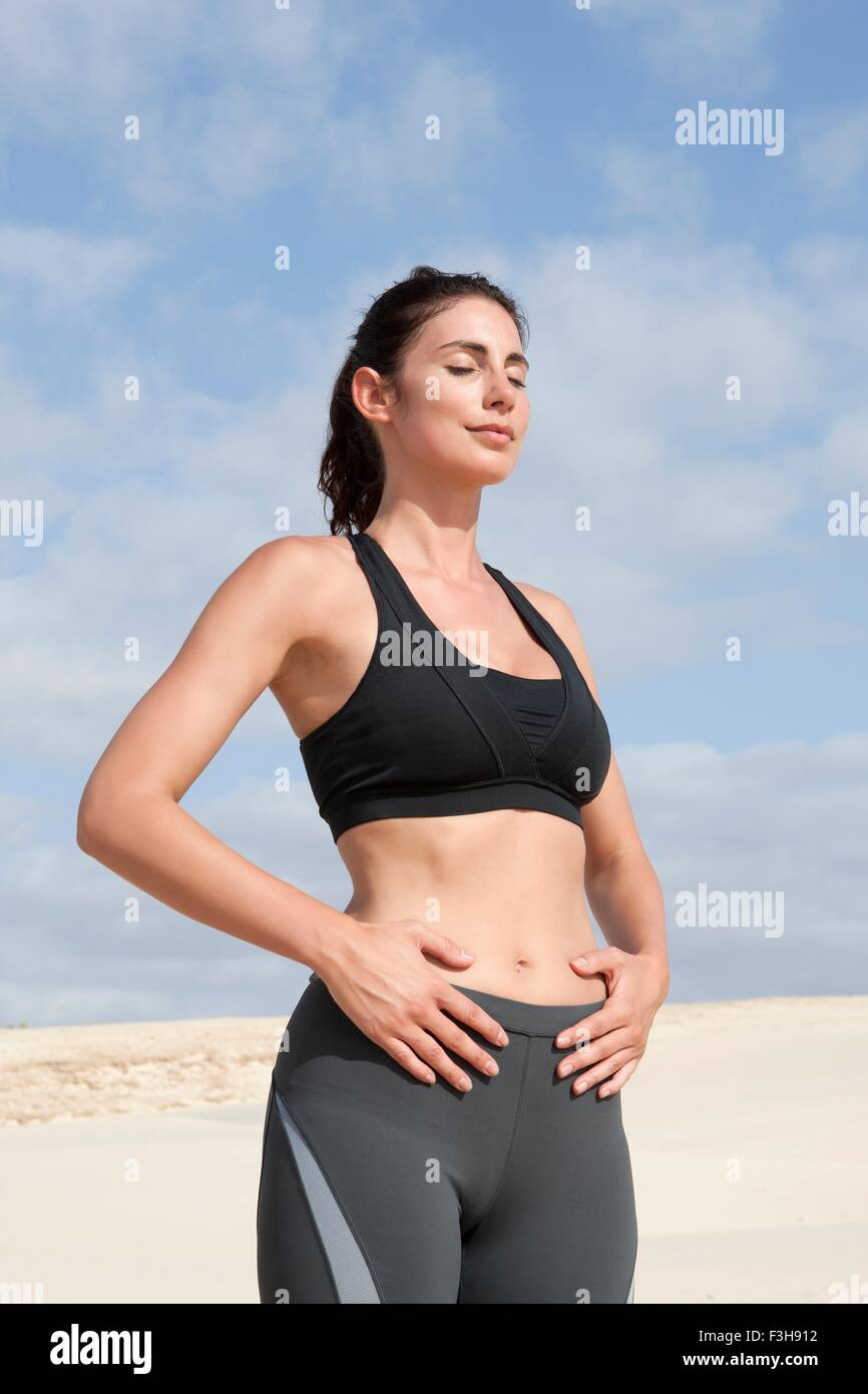 Mitte Erwachsene Frau, die das Training mit geschlossenen Augen und Hände auf Bauch am Strand Stockfoto