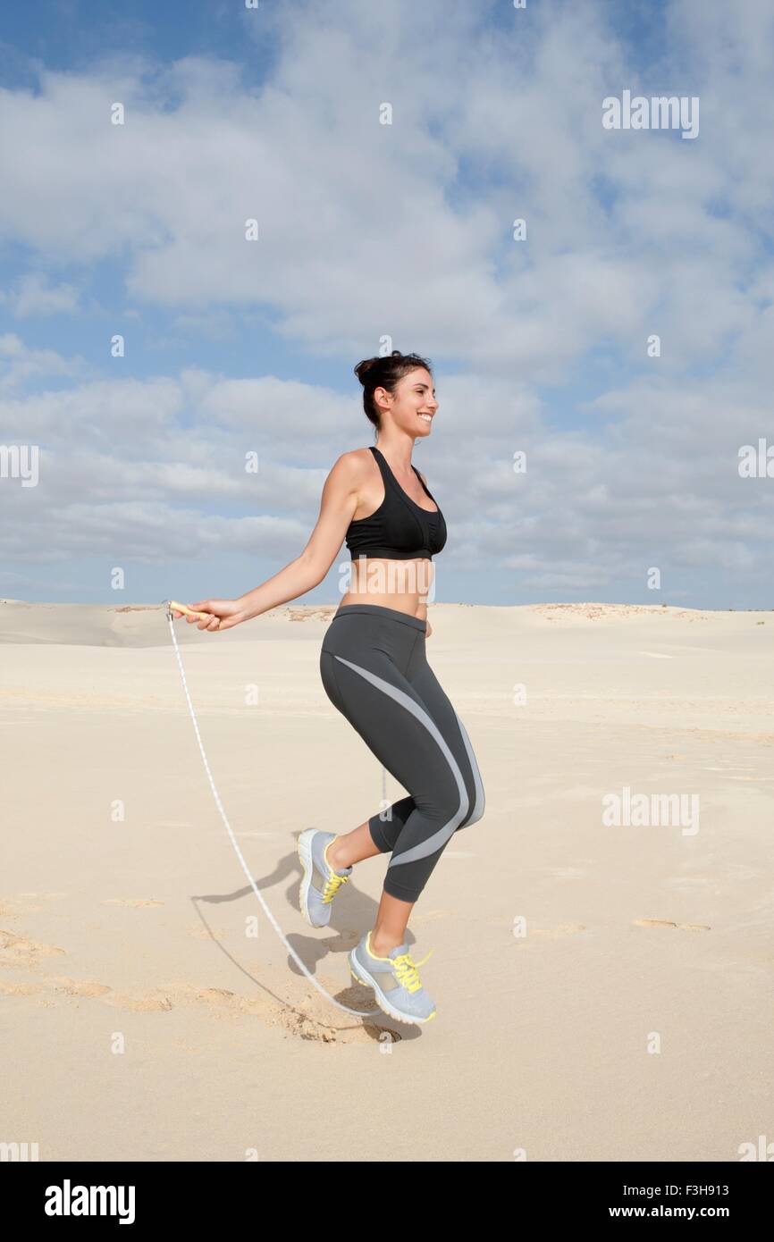 Mitte Erwachsene Frau, die das Training mit dem Springseil am Strand Stockfoto