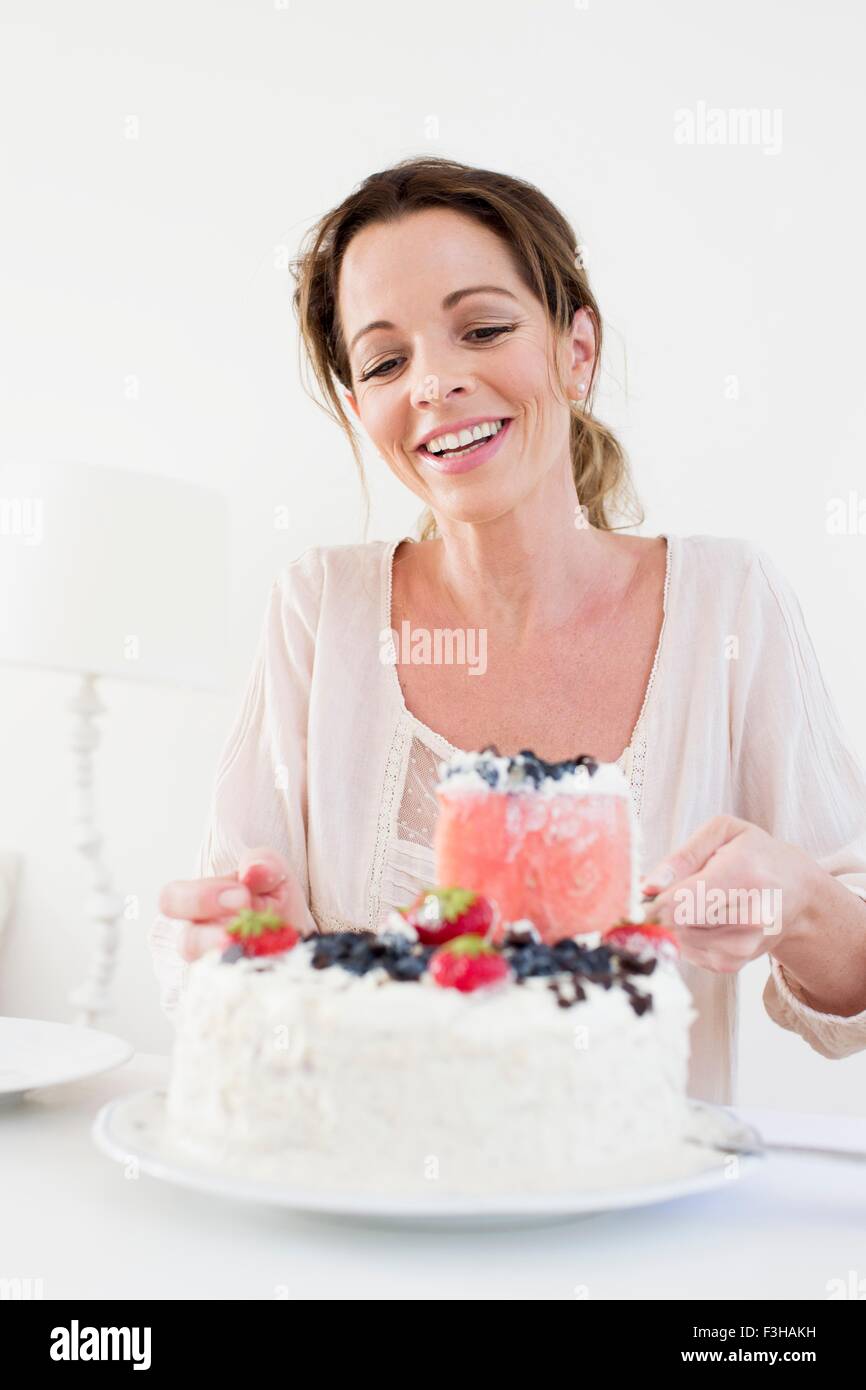 Reife Frau mit Obst bedeckt Kuchen blickte lächelnd Stockfoto