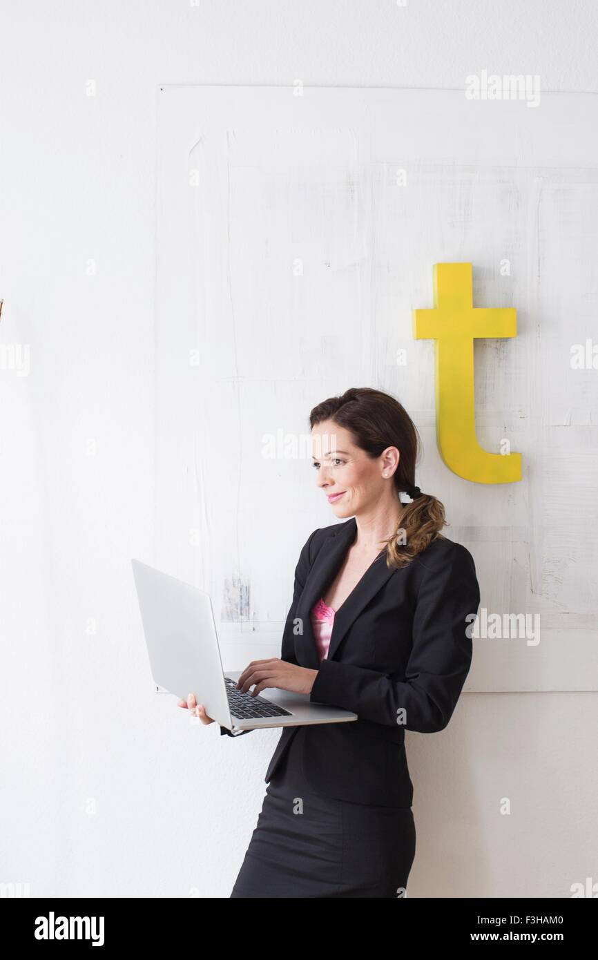 Reife Frau trägt Business Kleidung stehend mit laptop Stockfoto