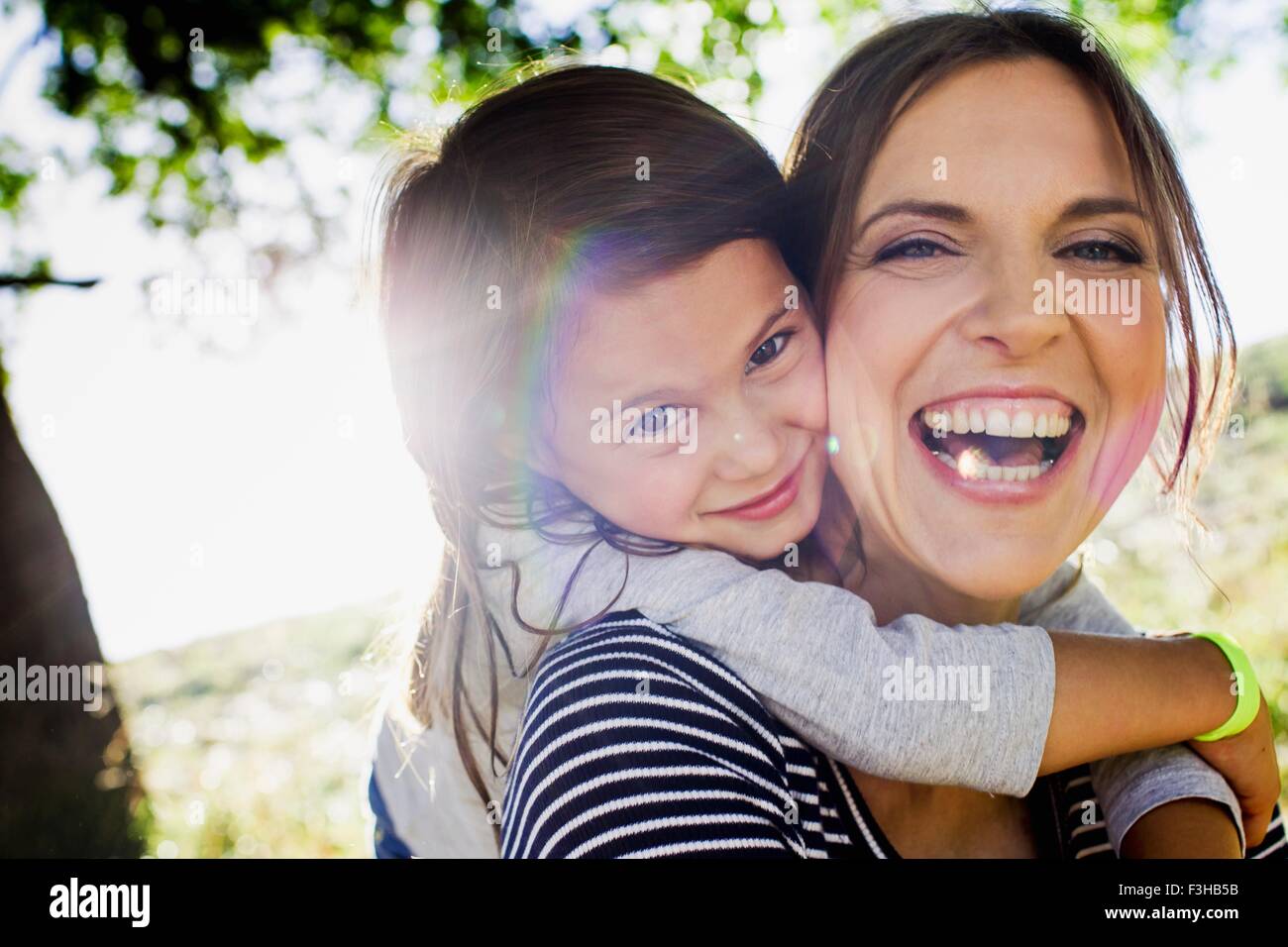 Porträt von Reife Frau und Tochter Schweinchen zurück im sonnigen park Stockfoto