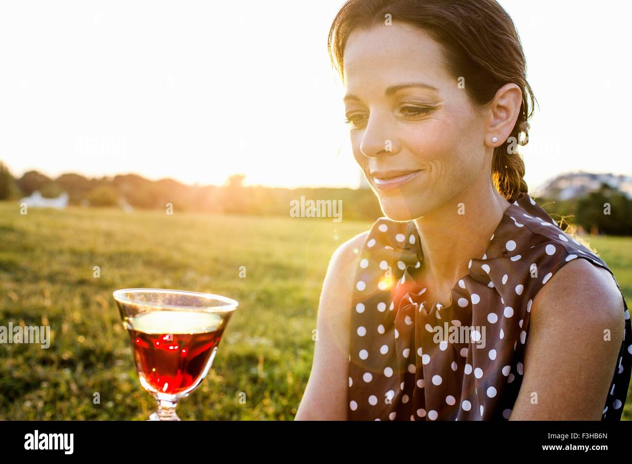 Reife Frau Betrachtung Rotwein im park Stockfoto