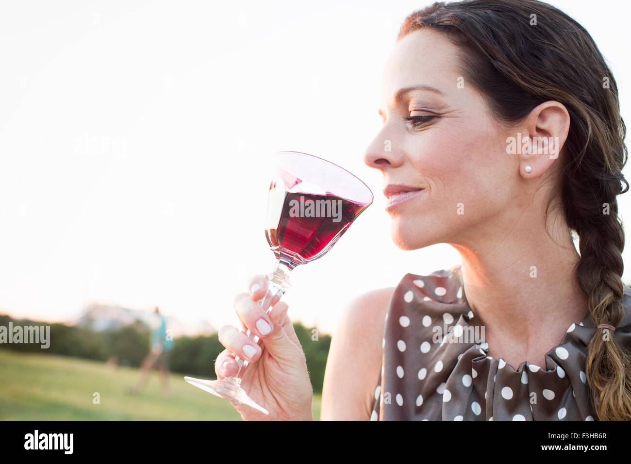 Reife Frau Glas Rotwein zu trinken, im park Stockfoto