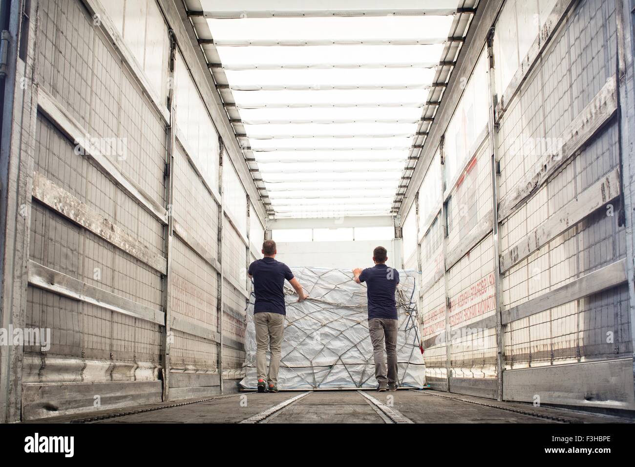 Arbeitnehmer, die Fracht im Luft-Fracht-Container schieben Stockfoto