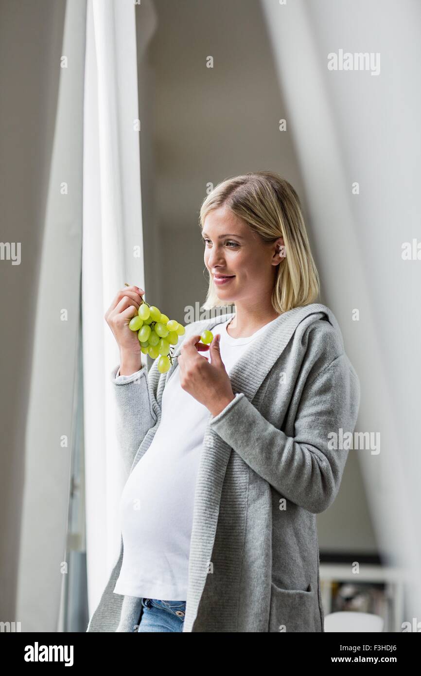 Volle Amtszeit Schwangerschaft junge Frau essen Trauben Stockfoto
