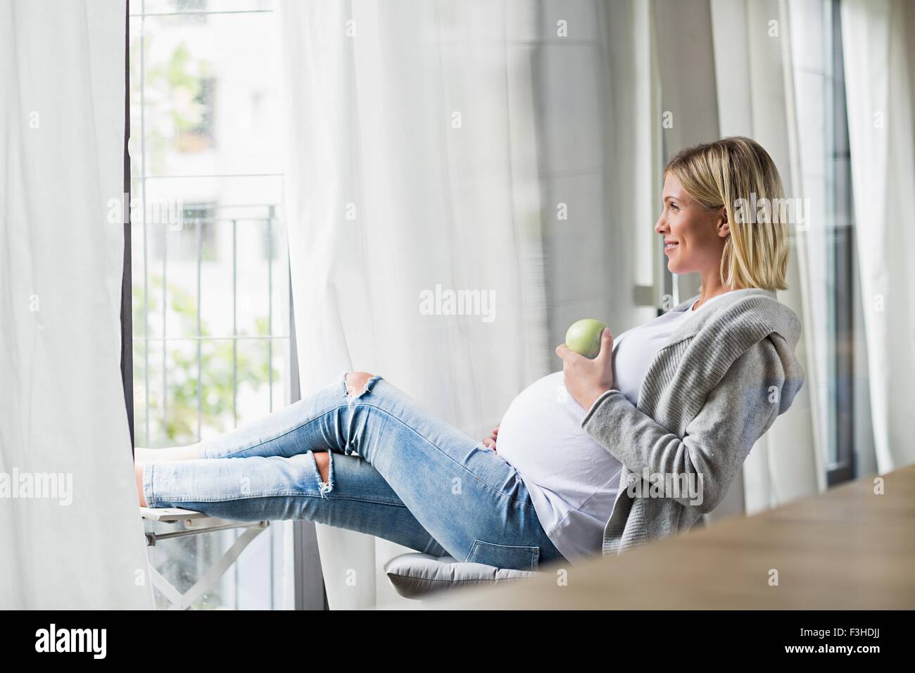 Volle Amtszeit Schwangerschaft junge Frau Essen Apfel Stockfoto