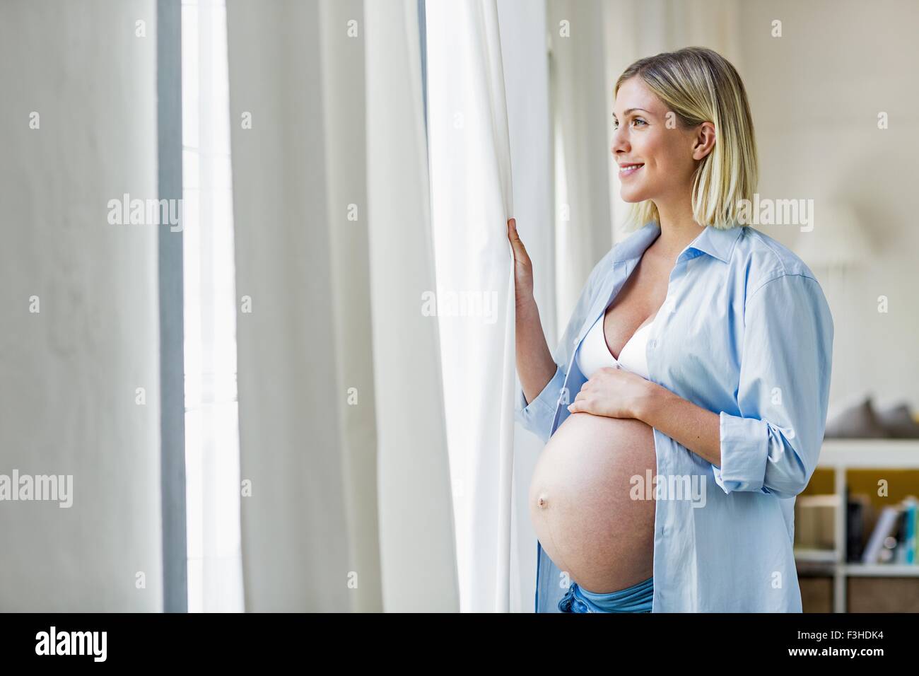 Volle Amtszeit Schwangerschaft junge Frau aus Fenster Stockfoto