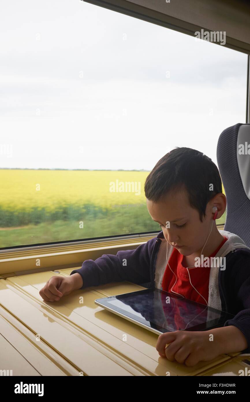 Junge im Zug lesen digital-Tablette Stockfoto