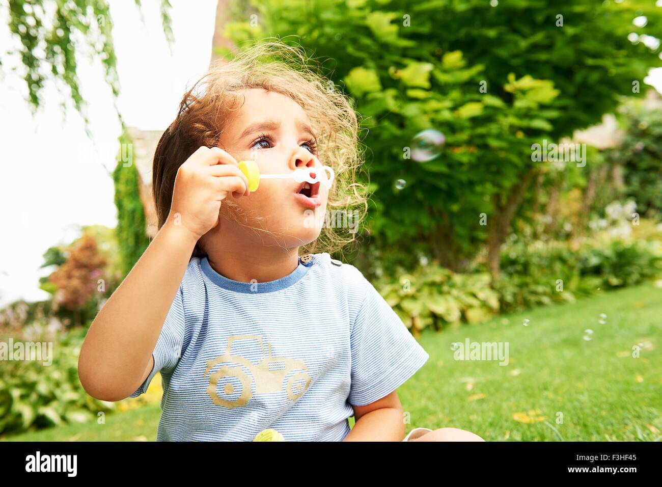 Porträt von netten Mädchen bläst Seifenblasen im Garten Stockfoto