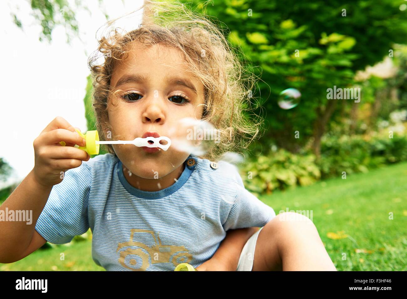 Porträt von netten Mädchen bläst Seifenblasen im Garten hautnah Stockfoto