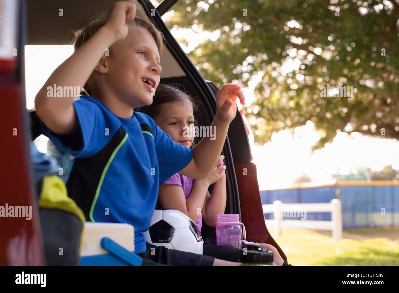 Junge und jüngere Schwester sitzen im Auto boot Fußball gucken Stockfoto