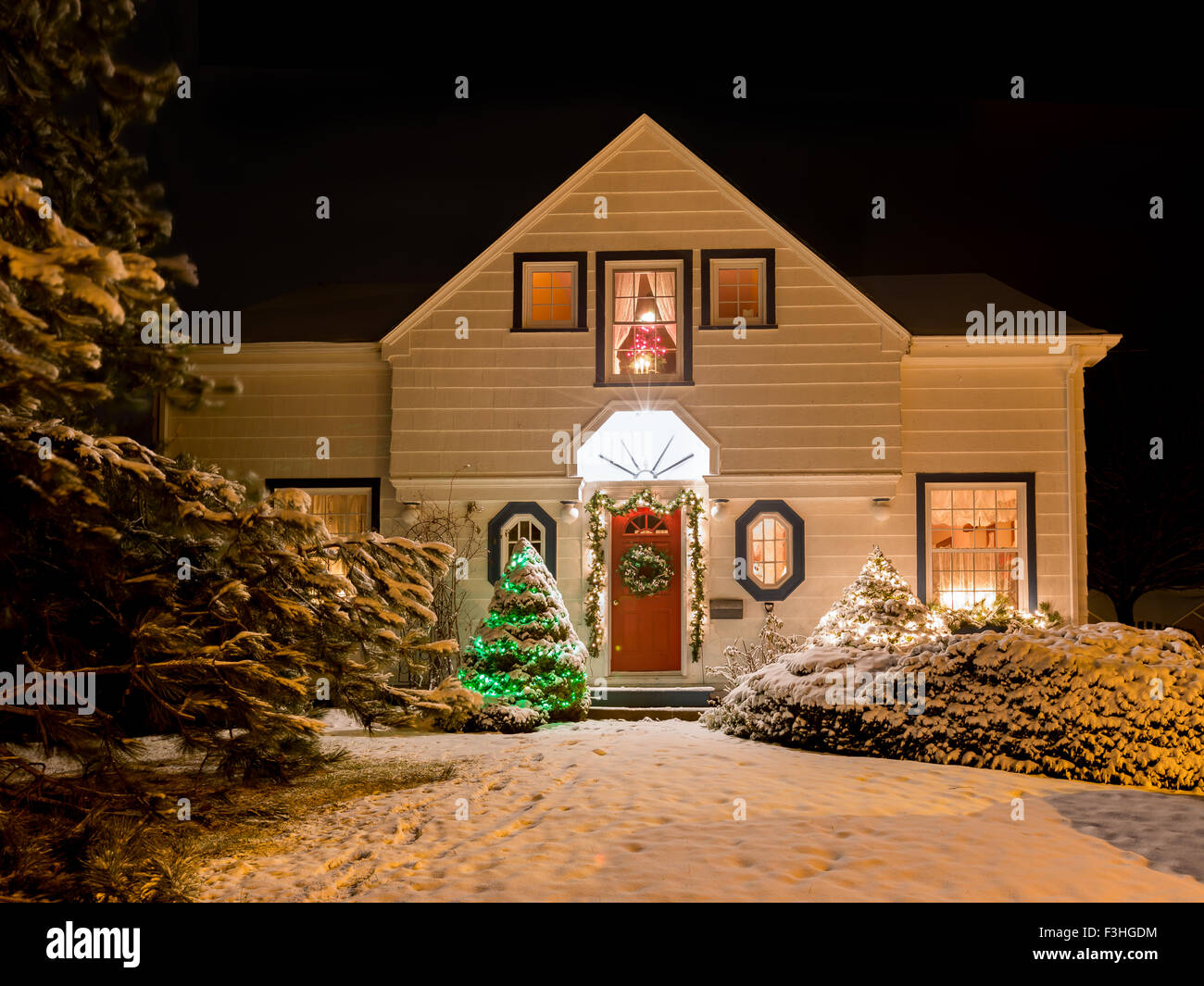 Ein Haus verziert mit Kranz, Kranz und Weihnachten Lichter ein einer klaren Winternacht. Stockfoto