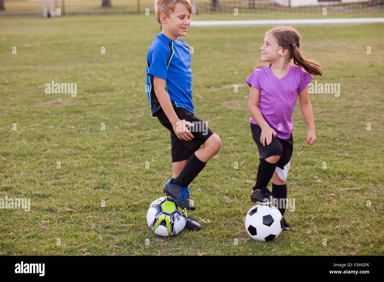 Junge und jüngere Schwester mit Fußbällen auf Praxis-Stellplatz Stockfoto
