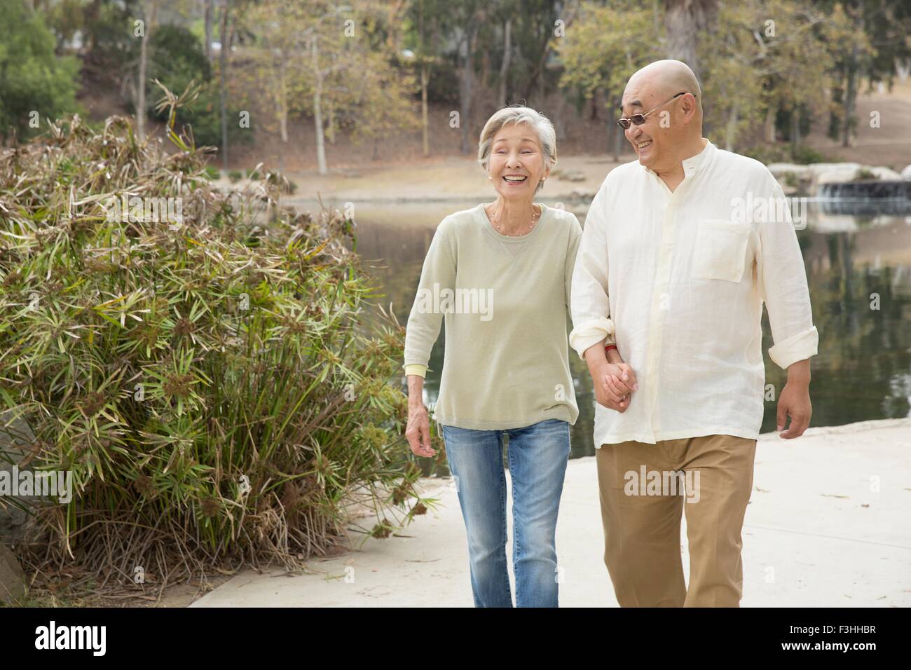 Älteres Paar zu Fuß Weg, Hand in Hand, lachen Stockfoto