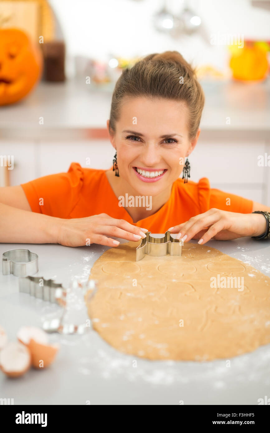 Fröhliche moderne Frau Halloween Kekse mit Gebäck Cutter ausschneiden, aus frisch gerollten Teig in eingerichteten Küche. Herkömmlichen Stockfoto